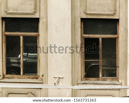 Abstract image of two windows at a high floor building where a vintage american car can be seen inside.