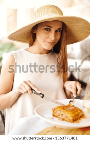 A young woman eating a tasty dinner in an Italian restaurant.
