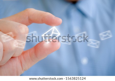 A man in a shirt holds an abstract envelope icon with his hand. The concept of mail and its sending. Close up. Royalty-Free Stock Photo #1563825124