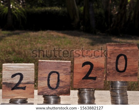 Word 2020 on wooden blocks with coins stack. New Year 2020 financial and saving money concept