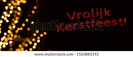 "Merry Christmas" Dutch language red letters text winter holidays concept poster picture on black background with yellow garland illumination frame 