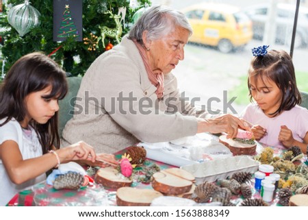 Grandmother teaching her granddaughters how to make christmas Nativity crafts - Real family
