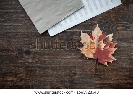 Notebook for notes and autumn red leaves lie on a dark wooden surface