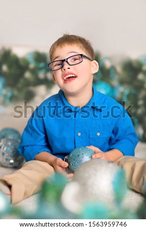 Vertical portrait of a Child with down syndrome with Christmas tree toys in Christmas decorations. At home.