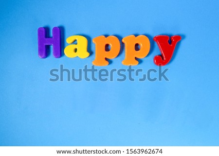 Plastic sign lettering Happy on blue paper background