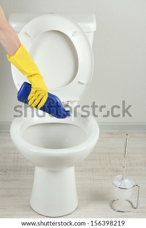 Woman hand with spray bottle cleaning a toilet bowl in a bathroom