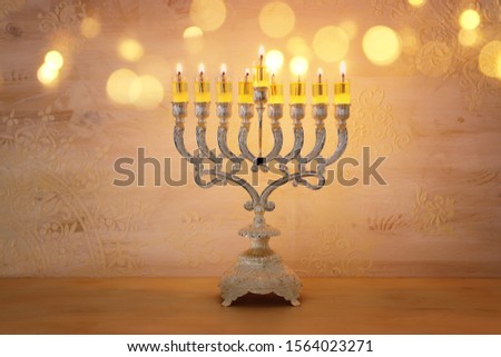 Religion image of jewish holiday Hanukkah with menorah (traditional candelabra) and oil candles over yellow background