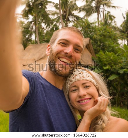 young happy and beautiful hipster couple taking selfie picture with mobile phone outdoors enjoying holiday at tropical nature background smiling and  exploring exotic tourist destination