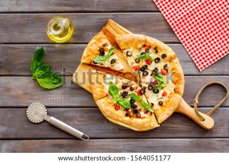 Pizza with tomato, basil, olives, cheese on dark wooden background top view