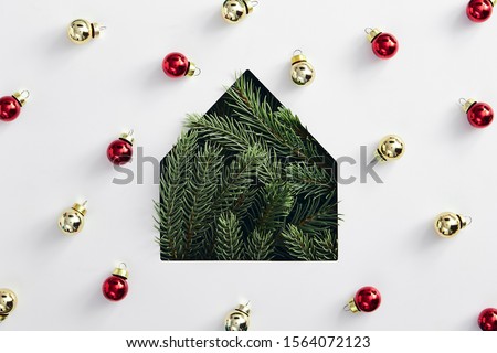 Christmas minimal concept - simple house silhouette made of christmas tree branch with bauble on white background. Flat lat, top view. Minimal house concept. Creative minimal. Holiday concept.