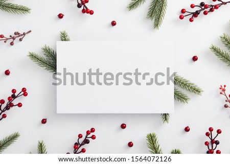 Christmas minimal concept - christmas composition made of evergreen tree branch and red berries. Flat lay, top view. White paper blank. Invitation background. Christmas card. Xmas holiday concept.