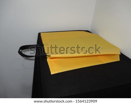 lying on Black table, Non woven yellow Bag, Eco Bag