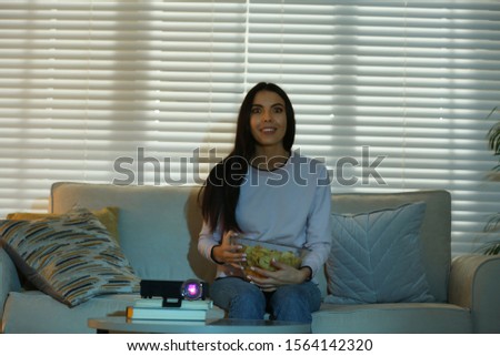 Young woman watching movie using video projector at home