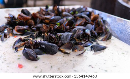Fresh mussels at grill pan. Seafood barbecue outdoors. Picnic healthy food, mussels in shells.Plenty of mussel shells cooking at large metallic pan.