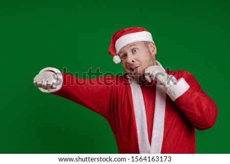 Emotional male actor in a costume of Santa Claus box and fights on a green chrome background