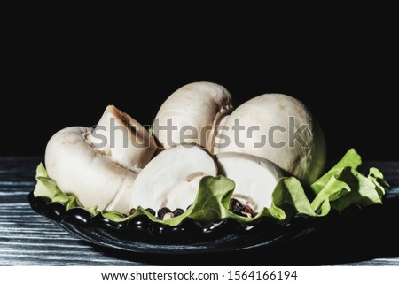 fresh champignons on an old surface with lettuce on a black background