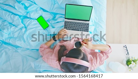 top view of asian woman use laptop to listen music or watch video with headset wearing on head and drink coffee