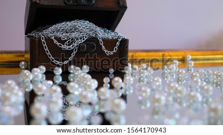  Antique jewelry trunk full with silver chain surrounded by white pearls. Reflection in the mirror.
