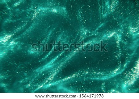 Abstract elegant, detailed mint glitter particles flow with shallow depth of field underwater. Holiday magic shimmering luxury background. Festive sparkles and lights. de-focused
