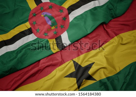 waving colorful flag of ghana and national flag of dominica. macro