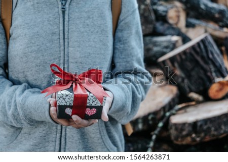 Gift box with red ribbon in woman's hand. Vintage tone picture. Selective focus.