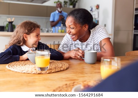 Grandparents Sitting In Kitchen With Grandchildren Eating Breakfast Before Going To School Royalty-Free Stock Photo #1564291684