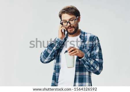 A man in a plaid shirt is talking on a review service phone