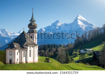 Classic panoramic view of scenic snow-capped Watzmann mountain top with historic pilgrimage church Maria Gern on a beautiful sunny day in spring, Nationalpark Berchtesgadener Land, Bavaria, Germany Royalty-Free Stock Photo #1564351759