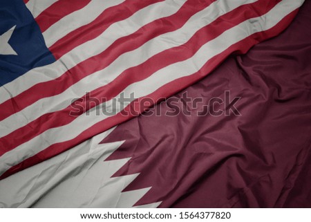 waving colorful flag of qatar and national flag of liberia. macro