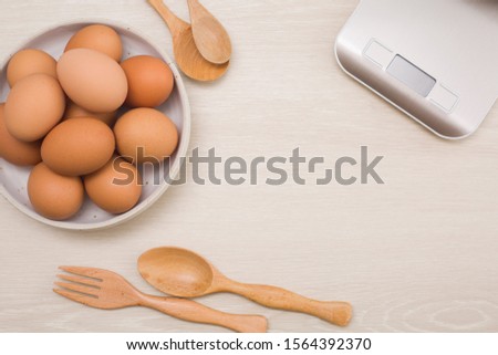 Fresh eggs on a bowl rustic background, wood spoon, weighing apparatus.The top view. View from above.