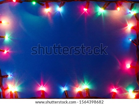Beautiful frame of garland with colorful lights on a blue background. Background to copy space and text.
