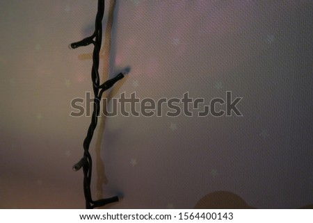 A photo of a turned off string of Christmas lights against a pink wallpaper with white stars