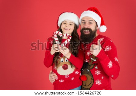 Christmas Carol. Father and daughter with candy canes christmas decorations. Family holiday. Santa claus family look. Bearded dad and cheerful little girl. Christmas time for kindness and goodness.