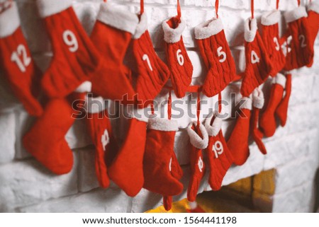 Beautiful background of Christmas decor at living room interior with burning white artificial eco-fireplace decorated traditional red knitted gift socks . Cozy New Year atmosphere. Selective focus