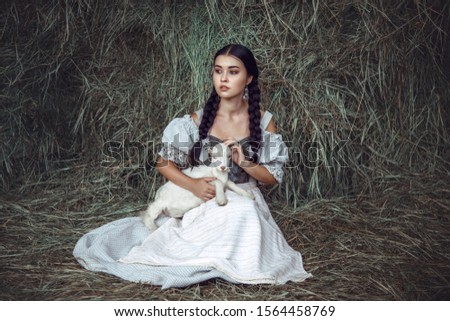 Funny picture a beautiful young girl farmer with white goat.outdoors.Portrait Of Beautiful Happy Dreamy women with animal.rural.countryside.