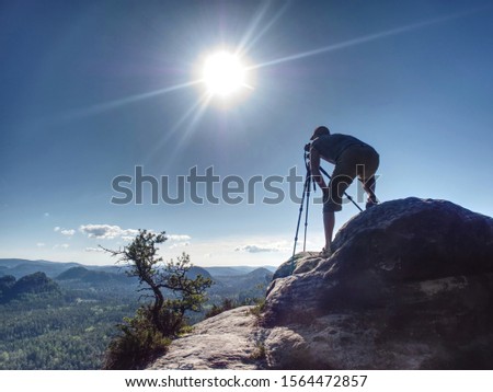 Silhouette of professional photographer working with camera and tripod, taking landscape shots during sunset. travelling and tourism concept.