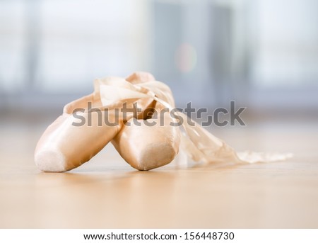 Close up view of pointes for ballet lying on the wooden floor in classroom