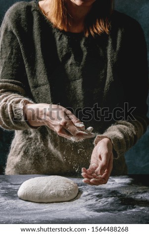 Process of making homemade bread dough. Female hands kneading dough on dark kitchen. Black table with flour. Home bread baking. Photo series.