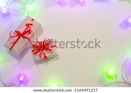 Background with New Year's festive garlands, glowing purple light, small gift boxes, with place for text.