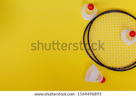 Badminton. Three shuttlecocks and two badminton rackets. Colored yellow background. Idea for a magazine. Healthy lifestyle concept.