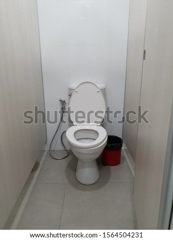The door is open for a clean white toilet.White public toilet