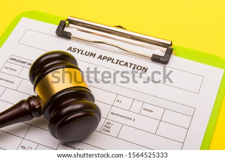 Asylum concept showing an application form for asylum on a yellow background with a gavel Royalty-Free Stock Photo #1564525333