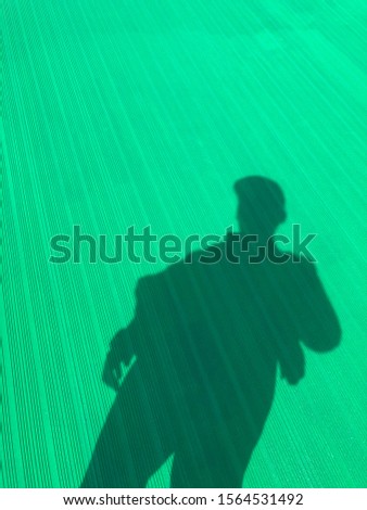 Shadow of a man under broad daylight with green background abstract photography