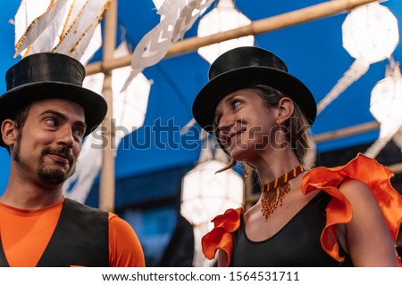 Stock photo of a couple of circus tightrope walkers dressed in orange dresses with blurred Chinese lanterns in the background at night. Lifestyle