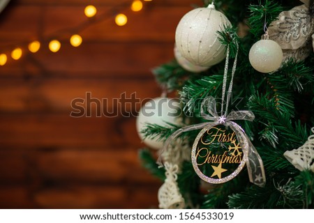 A small peach of a Christmas tree with a nice ornament which has a text on it - Firts Christmas. In the background it's a wooden panel and some lights bokeh. Very easy to use a Christmas banner.