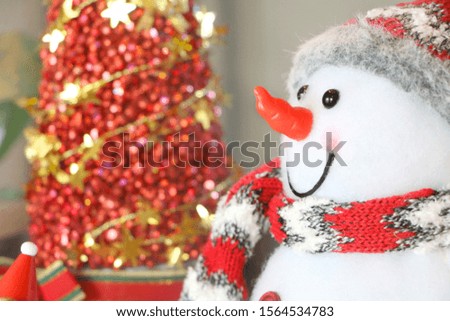 Close up snowman fur fabric doll on blurred red Christmas tree background, have copy space for put text.