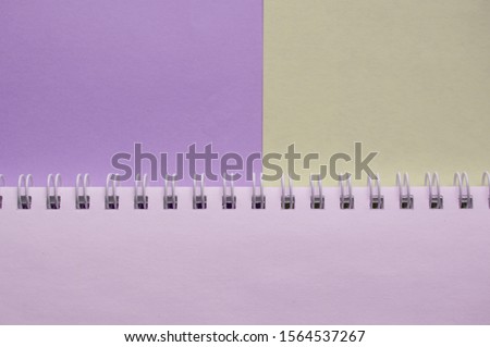Open empty spiral notebook on a two-tone background of lilac and gray, top view, minimalism with a copy of the space with a blank sheet on the table lay flat