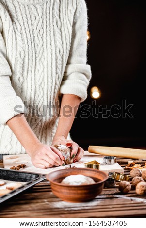 
Traditions to celebrate Christmas and New Year. Woman prepares homemade Christmas cookies. Black background.