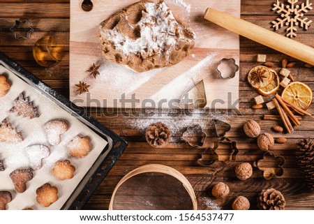 
Traditions to celebrate Christmas and New Year. Homemade cookies, ingredients for Christmas baking and kitchen utensils on a wooden table. Top view.