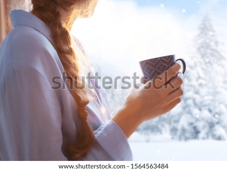 Woman sitting by the window, winter snow christmas concept 